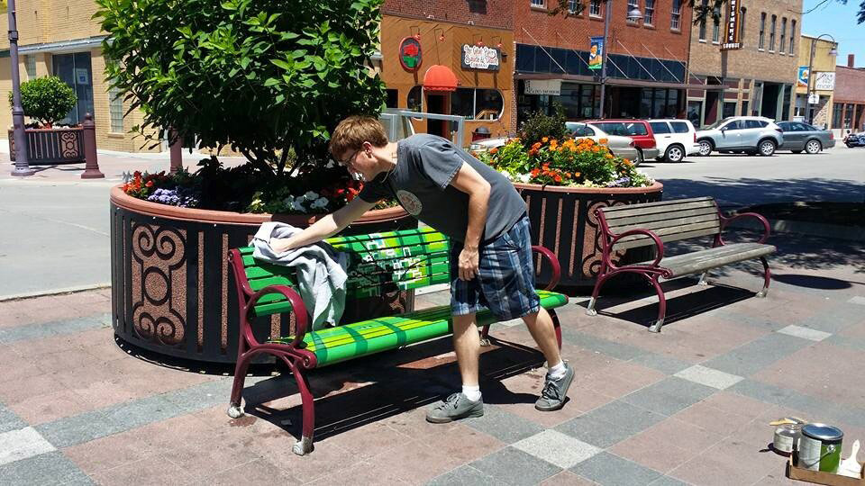 A volunteer cleaning a bench