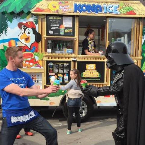 Darth Vader and an Kona Ice employee duel with shaved ice outside of a Kona Ice stand